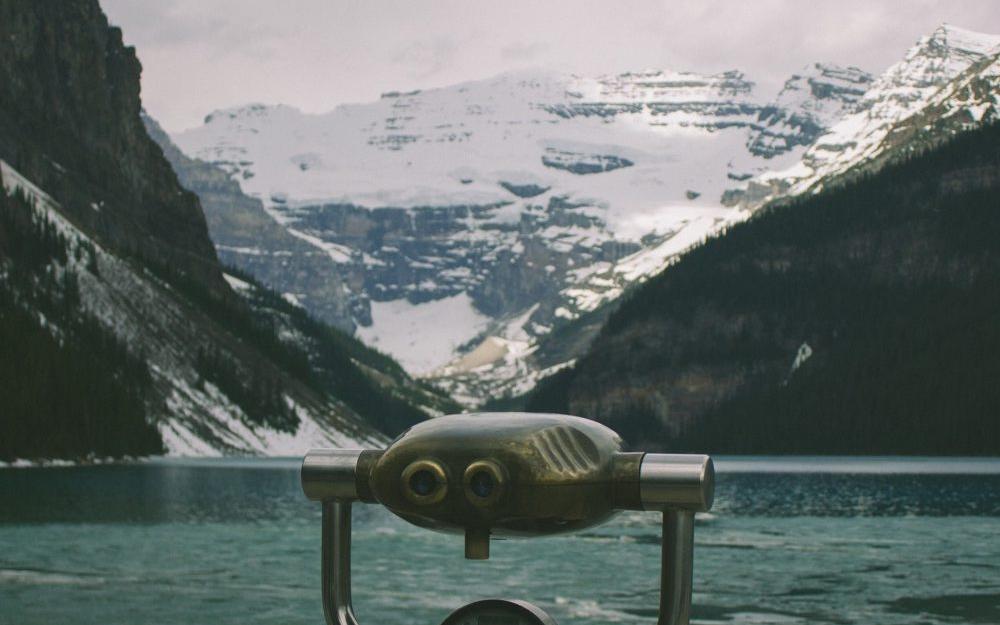 binoculars pointed out at a lake in front of a mountain 